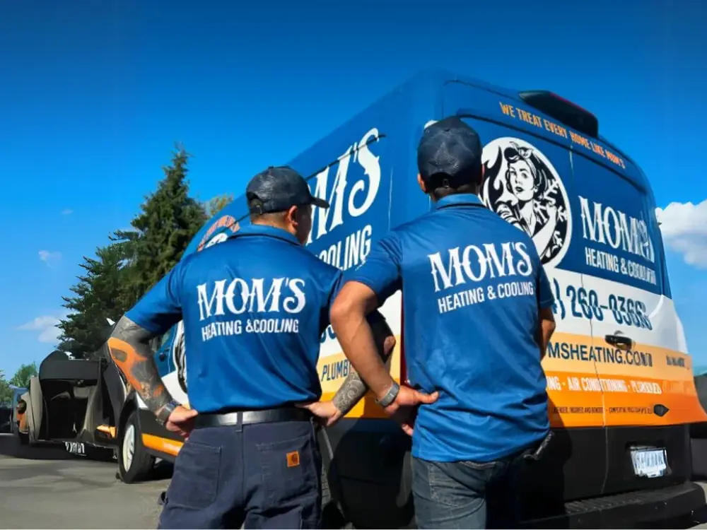 Two Mom's Heating & Cooling technicians in branded shirts at a company van